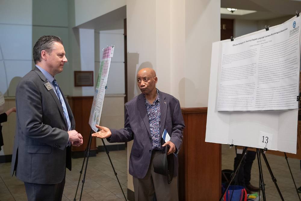 Dr. Nagnon Diarrasouba discussing Maximilian Young's poster with guest.